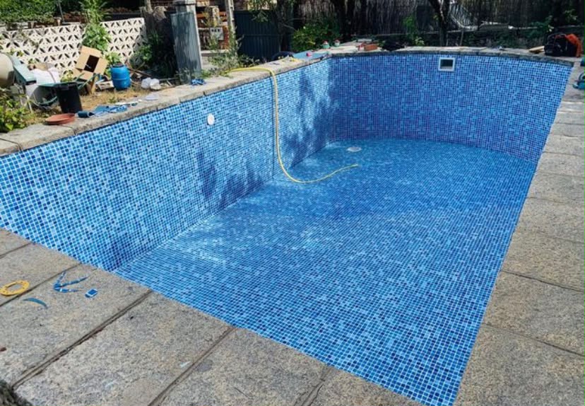 Piscina renovada con gresite azul y coronación de granito