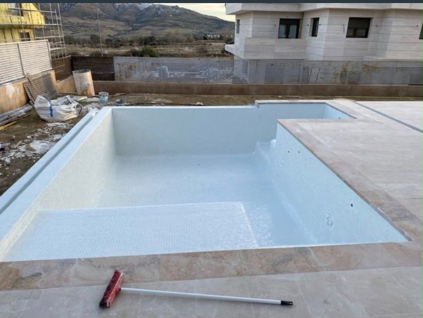 Piscina de obra nueva terminada en gresite blanco con coronación de piedra